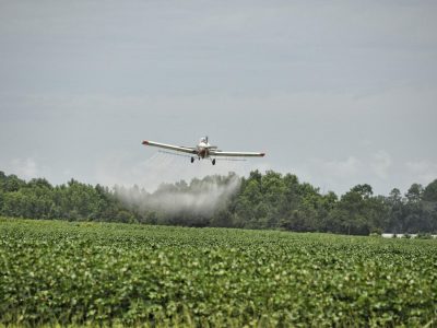 a crop duster sprays pesticide on a non-native-run farm field on a reservation.
