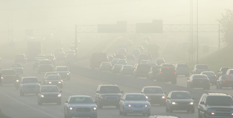 cars travel down the road in a sea of smog 