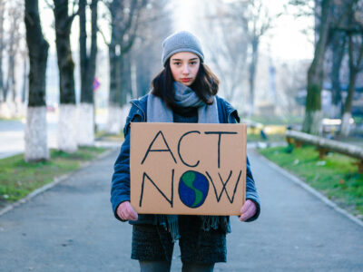 Young woman activist holding a climate change sign that says 